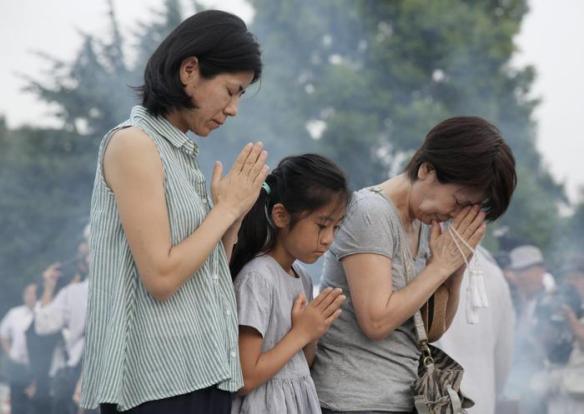 People offer prayers for victims of the 1945 Hiroshima atomic bombing, in front of a cenotaph at the Hiroshima Peace Memorial Peace Park, in Hiroshima, Japan, early morning 06 August 2015. Hiroshima is marking the 70th anniversary of the atomic bombing of the city on 06 August.  ANSA/KIMIMASA MAYAMA